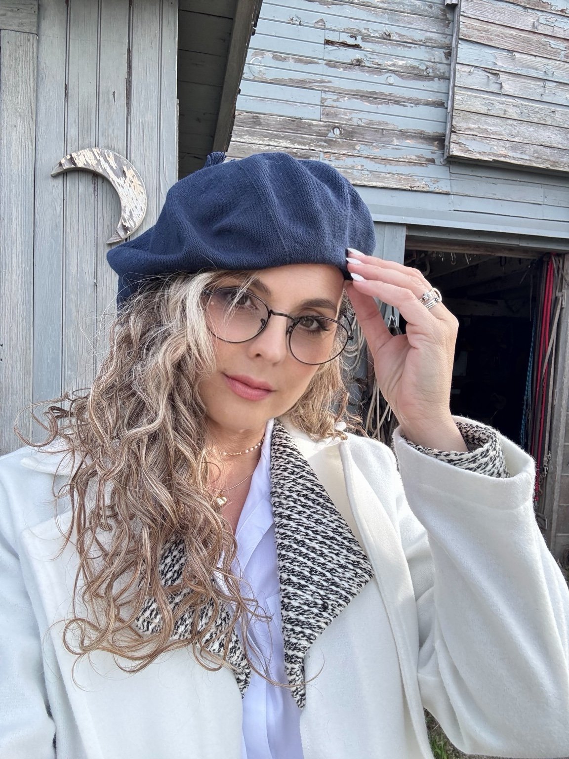 Luciana Castro with blue beret and glasses beside the stable